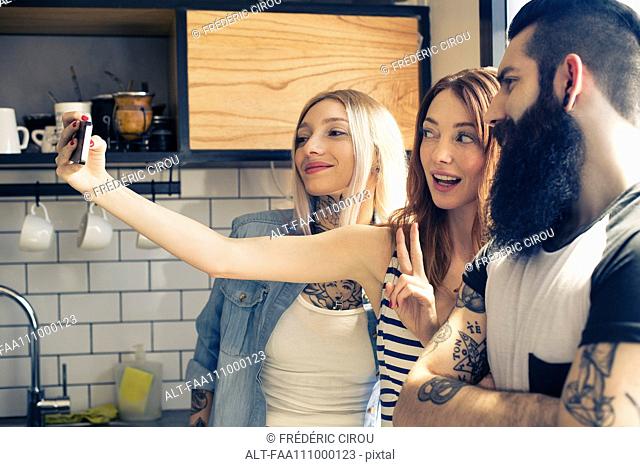 Friends posing together for selfie with smartphone
