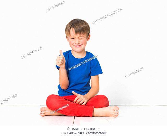 cool, six year old boy with red trousers and blue shirt on white floor