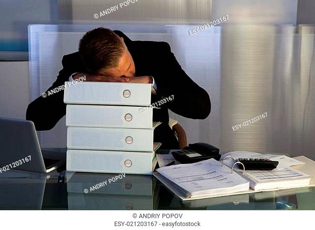 Exhausted businessman sleeping an a stack of files