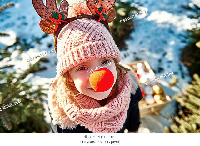 Girl in christmas tree forest with red nose, high angle portrait