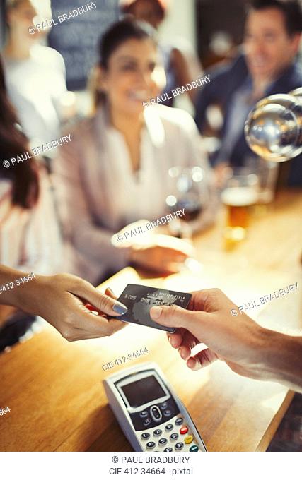 Woman paying bartender with credit card at bar