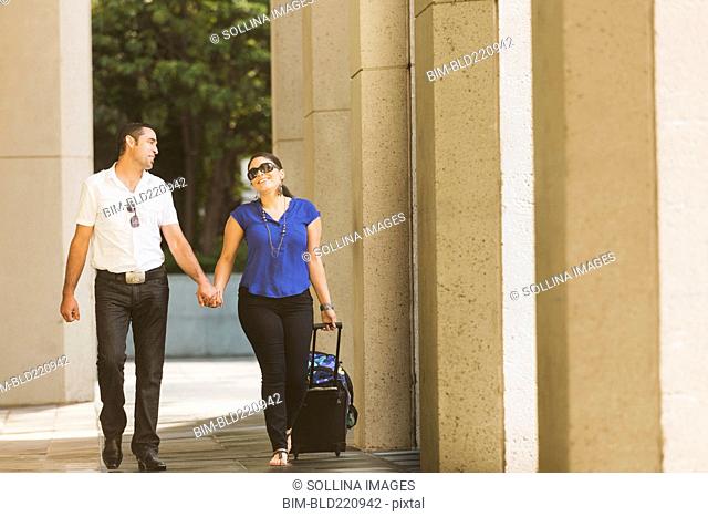 Hispanic couple holding hands under columns