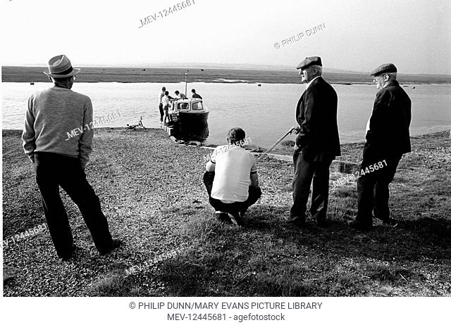 Old men watch as a small pleasure boat is launched into the River Loughor at Penclawdd in the north of the Gower Peninsula, Swansea, South Wales
