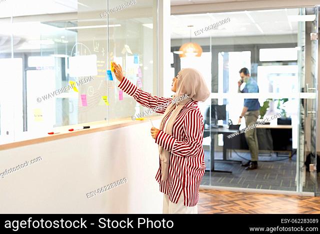 Middle-east woman in hijab in office brainstorming with post it card