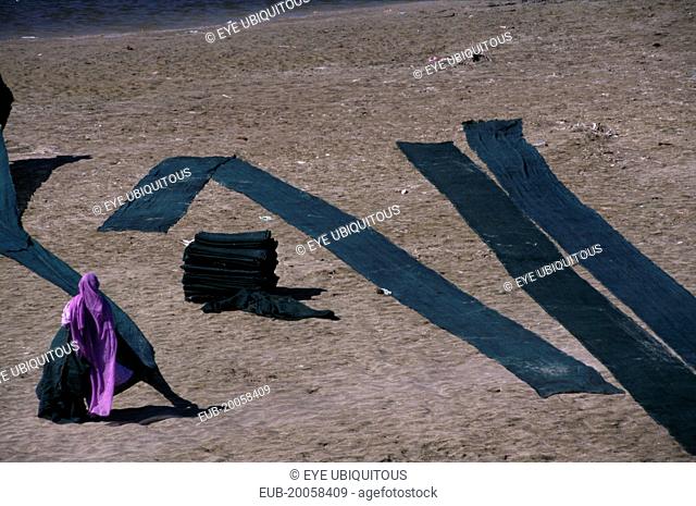 Woman drying dyed cloth on the edge of the Yamuna River