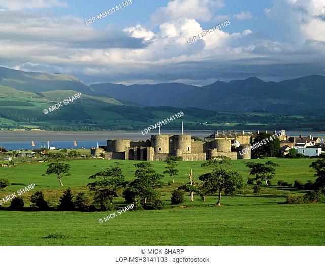 Wales, Anglesey, Beaumaris. A general view of Edward I's Beaumaris Castle looking south to the Menai Strait and the mountains of Snowdonia