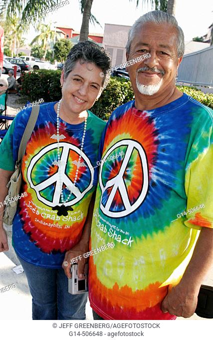 Annual satire parade, parody, Hispanic couple, tie-dye shirts, peace symbol. King Mango Strut. Coconut Grove. Florida. USA