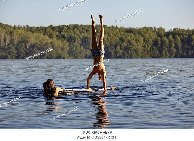 Man doing a handstand on a paddleboard in a lake