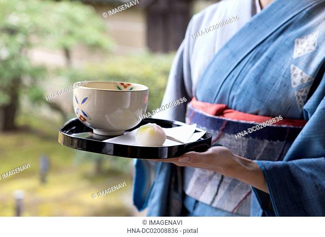 Young Japanese woman in kimono with tray