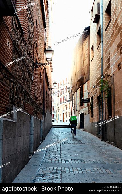 Madrid, Spain - November 1, 2019: Uber Eats rider cycling through an alley in old Madrid