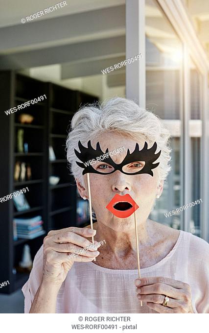 Senior woman hiding behind paper masks