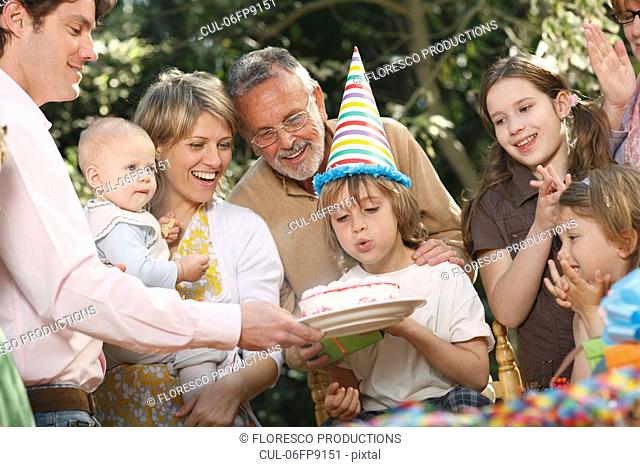 Young boy blowing out candles at party