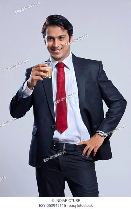 Smiling businessman drinking tea over gray background