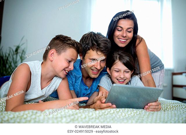 Happy family using digital tablet in bedroom