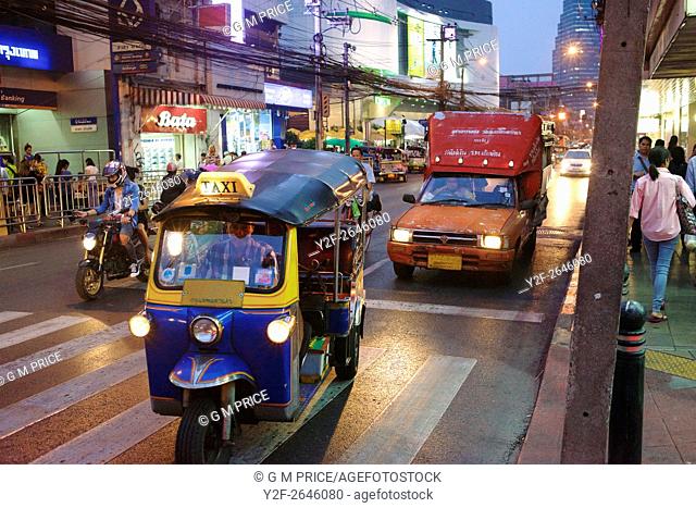 tuk tuk taxi, motorcyle and utility transport at lights in downtown Bangkok