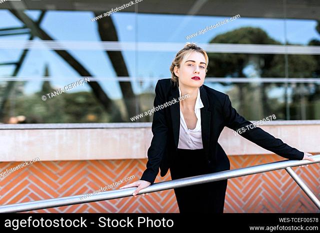 Portrait of young businesswoman wearing black pantsuit standing in front of an office building