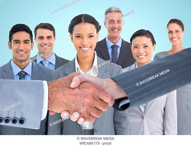 Composite image of Handshake in front of business people with blue background