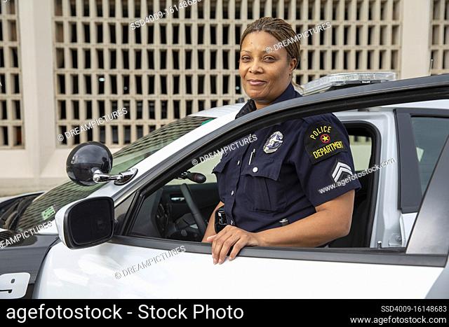 Policewoman standing in door of Police car looking towards camera smiling