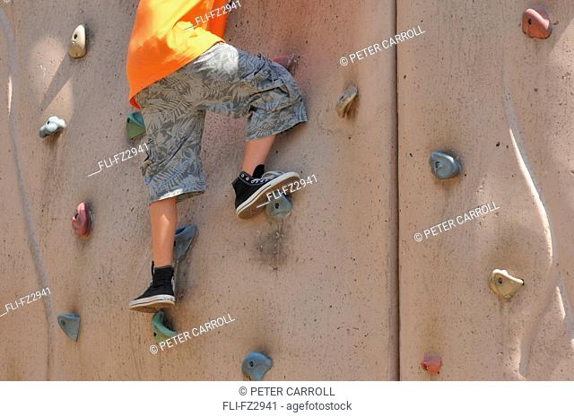 Young boy climbing rock wall at playground
