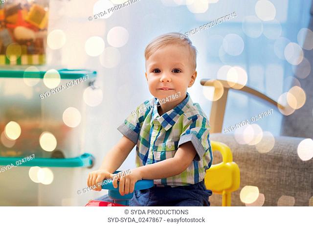 happy little baby boy driving ride-on car at home