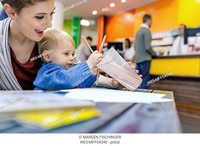 Little boy with mother drawing at table in pharmacy