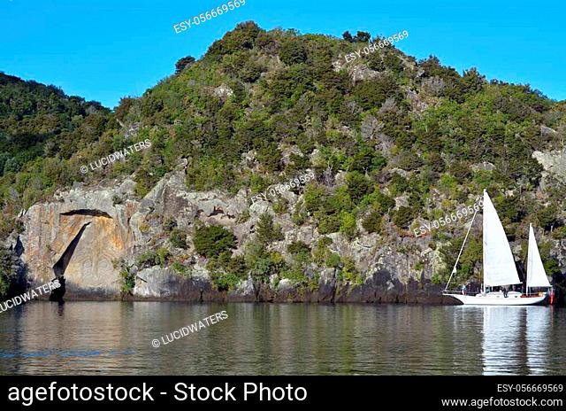 Sail boat sailing near the iconic Maori Rock Carving at lake Taupo in the North Island of New Zealand