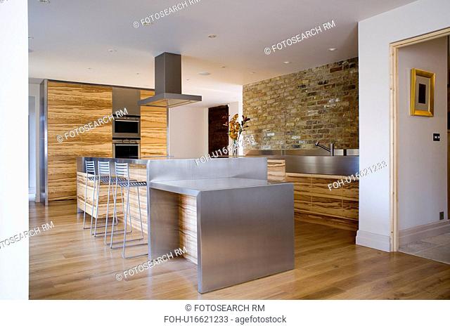 Wooden flooring and stainless steel island unit in modern country kitchen