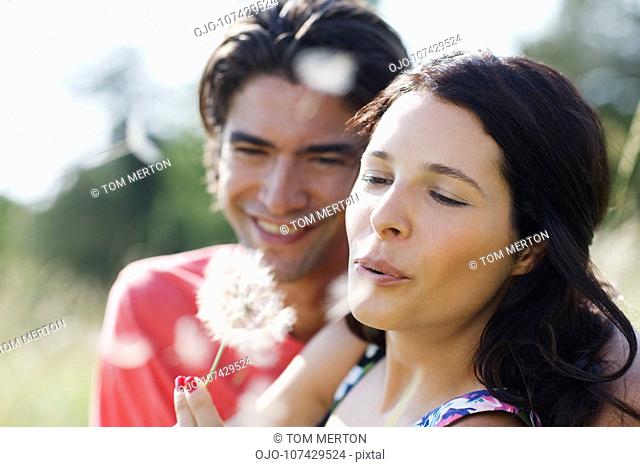 Couple blowing dandelion seeds together