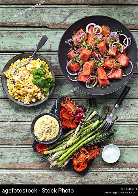 Grilled vegetables with dip, salad with watermelon, corn with chili and coriander