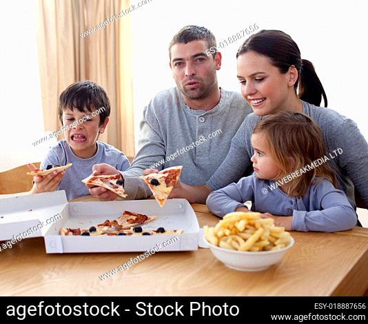 Parents and children eating pizza and fries on a sofa