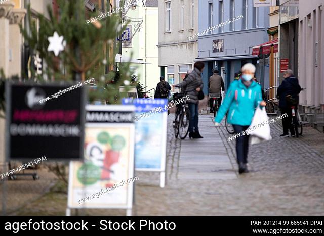 14 December 2020, Brandenburg, Senftenberg: A passer-by with mouth and nose protection walks through a shopping street in Senftenberg in the southern...