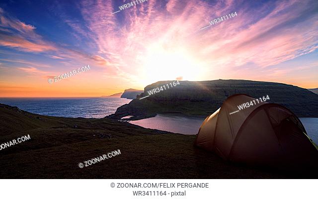 camping tent near a mountain lake with a beautiful sunset and sky