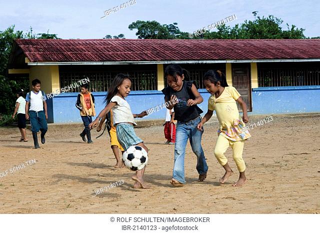 School children playing soccer in the schoolyard before classes start in a village with no road access in the rainforest of the Oriente, Curaray, Ecuador