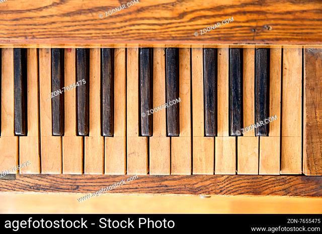 Close up top view of old wooden piano wtih brown and black keys