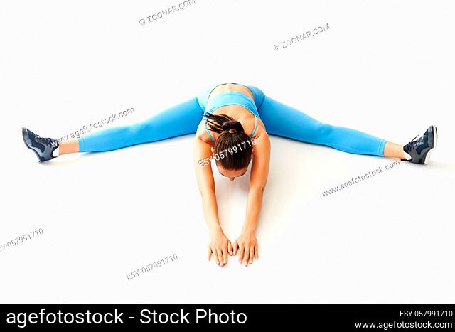 Top view of sporty woman doing stretch exercise and split twine on white background