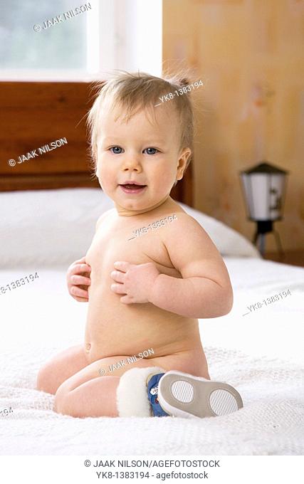 Happy Emotional Naked Ten Month Old Baby Girl Kneel Down on Bed