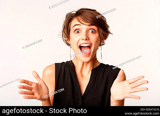Close-up of amazed happy girl clasp hands, standing surprised over white background