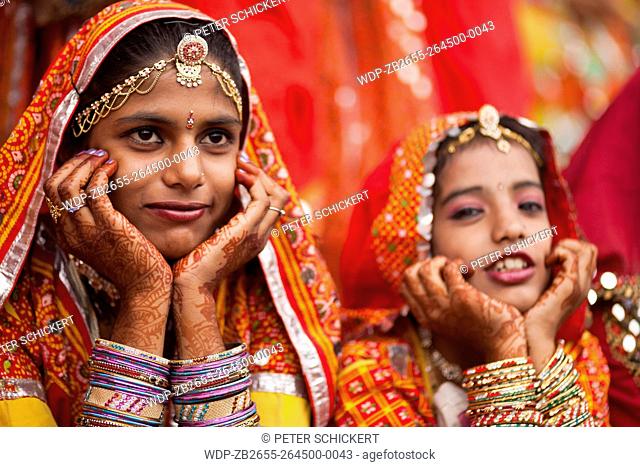 Junge Frauen in der typischen farbenfrohen Tracht der Rajasthanis und mit Henna bemalten Händen beim Kamel- und Viehmarkt Pushkar Mela in Pushkar, Rajasthan