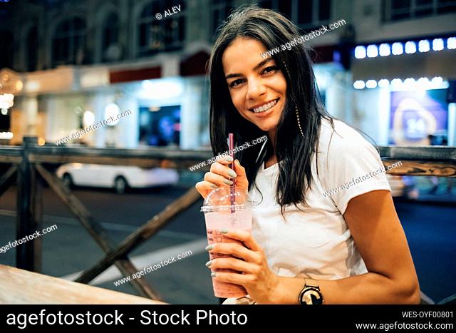 Happy beautiful woman with smoothie at sidewalk cafe