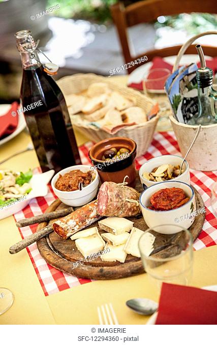 Wooden plate with antipasti (sausage, cheese, olives, oil pickled mushrooms and dried tomatoes)