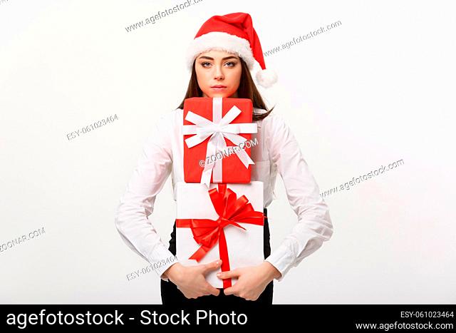 Business Concept - Beautiful young caucasian business woman with santa hat holding a lot of gift boxes with worry facial expression