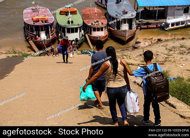 PRODUCTION - 08 November 2023, Brazil, Parintins: People board boats with their luggage. The drought makes everyday life difficult for the river dwellers