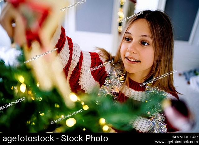 Girl decorating Christmas tree at home