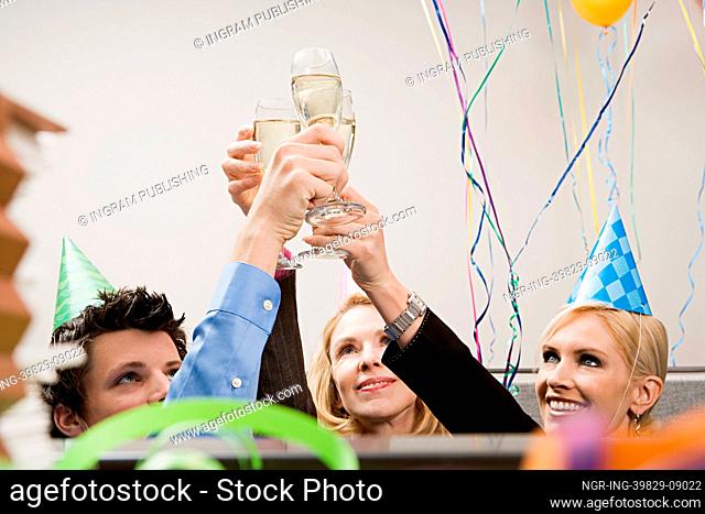 Three office workers toasting with champagne