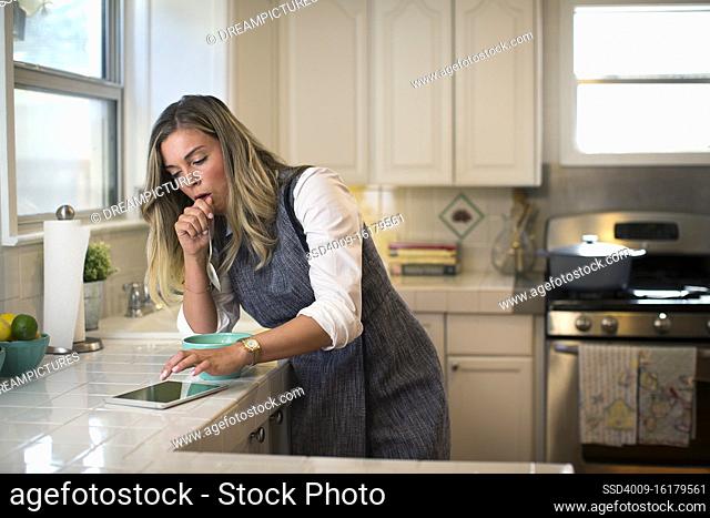 Coughing young woman in her kitchen, eating breakfast getting on her iPad
