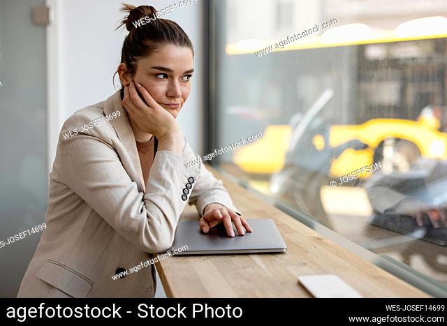 Stressed businesswoman with laptop on table in front of window at office