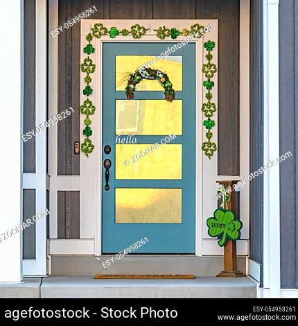 Square frame Outdoor steps leading to the entrance of a charming home. Beautiful clover ornaments can be seen on the glass paned blue front door