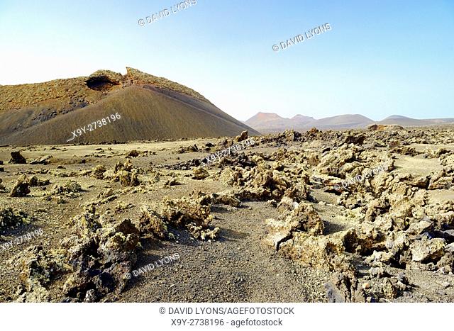 Crossing cinder field to volcanic cone of Caldera de los Cuervos. Timanfaya National Park, Lanzarote, Canary Islands, Spain