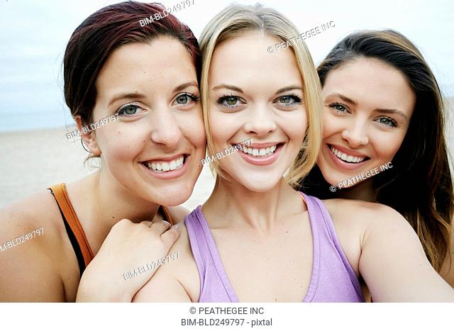 Portrait of smiling Caucasian women cheek to cheek on beach