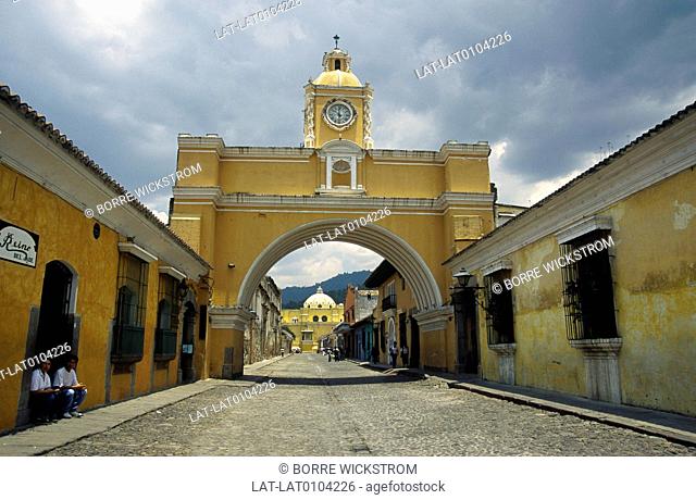 Arco, arch of Santa Catalina across street. Historical, colonial style. View through arch. Houses. Church dome